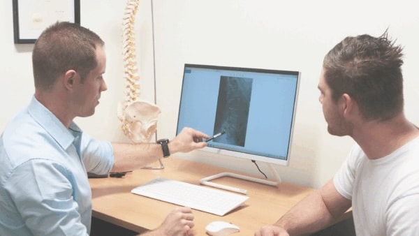 Dave from Regenerate Chiropractic pointing at an x-ray of a spine
