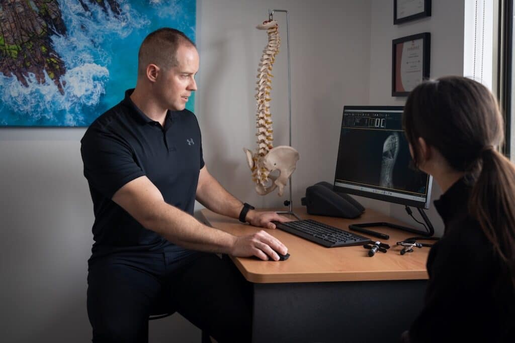 chiropractor going through spinal x ray with patient